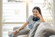 © wichayada - Relaxing at home. Portrait of a young woman smiling on white couch
