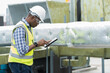 © amorn - Male engineer worker working with digital tablet inspecting quality ventilation, air conditioning at rooftop of building. Male technician maintenance pipe system for ventilation at construction site