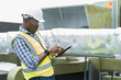 © amorn - Male engineer worker working with digital tablet inspecting quality ventilation, air conditioning at rooftop of building. Male technician maintenance pipe system for ventilation at construction site