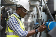 © amorn - Male plumber engineer inspecting quality of work at sewer pipes area at construction site. African American male engineer worker check or maintenance sewer pipe network system at rooftop of building