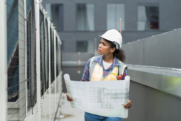 female engineer worker working, holding blueprint and inspecting structure of building at rooftop of