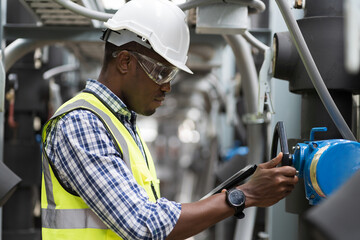 Wall Mural - Male plumber engineer inspecting quality of work at sewer pipes area at construction site. African American male engineer worker check or maintenance sewer pipe network system at rooftop of building