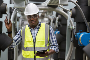 Wall Mural - Male plumber engineer inspecting quality of work at sewer pipes area at construction site. African American male engineer worker check or maintenance sewer pipe network system at rooftop of building