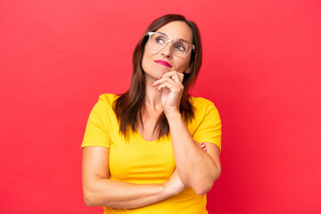 Wall Mural - Middle-aged caucasian woman isolated on red background having doubts