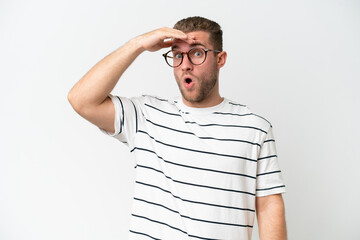 Canvas Print - Young handsome caucasian man isolated on white background doing surprise gesture while looking to the side