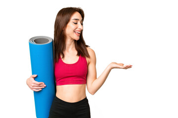 Canvas Print - Young sport caucasian woman going to yoga classes while holding a mat over isolated chroma key background with surprise expression while looking side