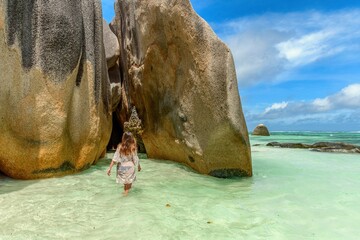 Wall Mural - Young woman wearing summer clothes, standing on tropical beach with turquoise ocean