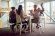© luckybusiness - Young business people are sitting around the table during a lunch break in the company building and having a good time while eating pizza. Business, people, company