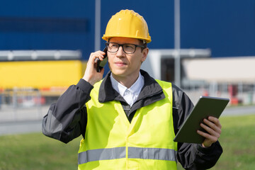 Poster - Logistician with phone and digital tablet on a background of logistic center