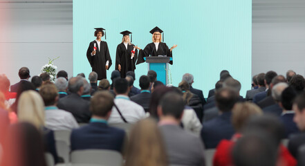  Graduate students of honor and a professor standing on a podium in front of people