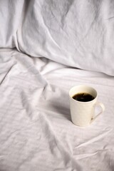 Sticker - White ceramic mug with freshly brewed coffee atop a bed of crisp, white sheets