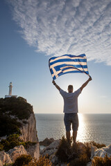 Wall Mural - man with greece flag looking at sunset above the sea