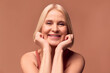 © Velista production - Modern beautiful retired woman posing on beige background and smiling. Skin care and women's health.