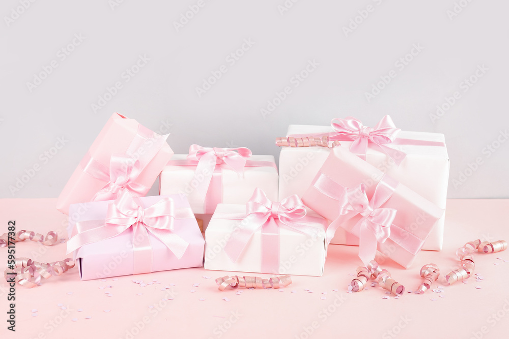 Gift boxes with bows, confetti and serpentine on pink background
