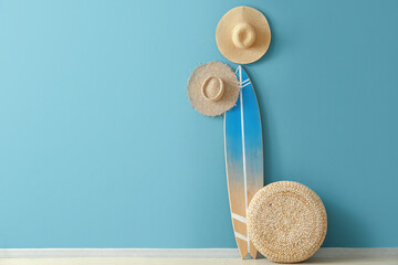 Canvas Print - Straw hats with surfboard and pouf near blue wall in room