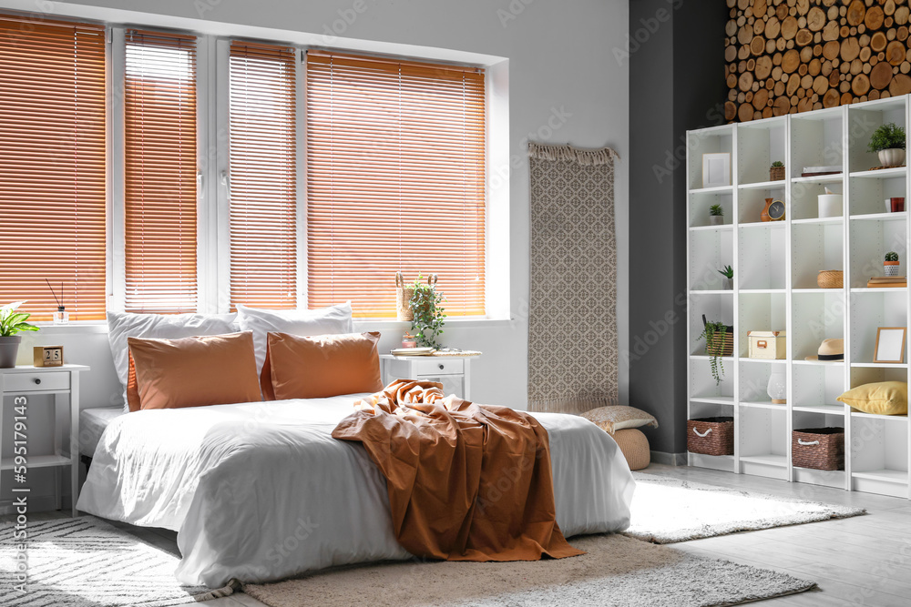 Interior of light bedroom with tables and shelving unit