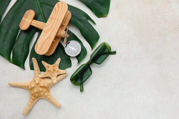 Wall Mural - Composition with sunglasses, airplane, starfishes, compass and monstera leaf on light background