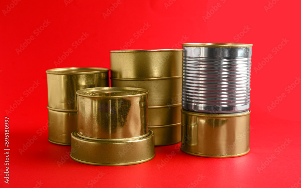 Stacks of tin cans with fish on red background