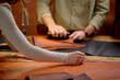 © Roman - woman's arms measuring leather for sewing, man using brush to clean the surface of material from the dust. close up cropped side view shot, focus on arms. blurred background