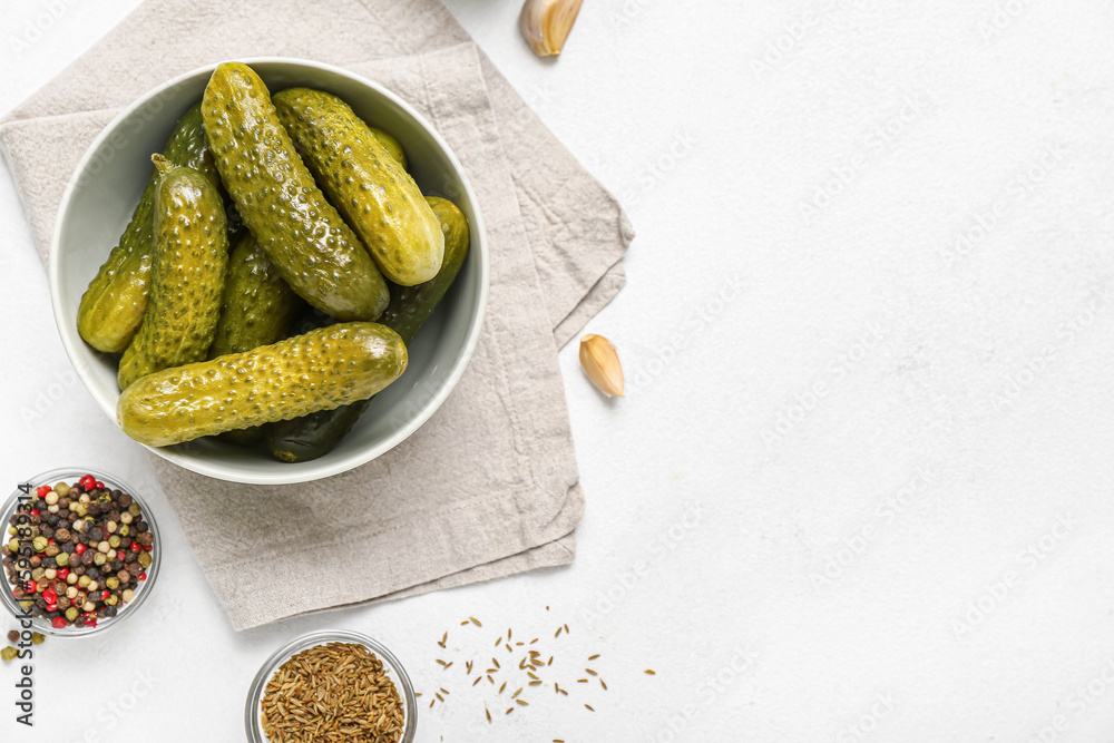 Bowl with tasty fermented cucumbers on light background