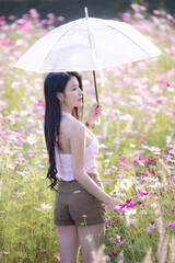 Wall Mural - Beautiful woman happy traveler walking in the flowers garden. Young woman smile and relaxing with happy  around outdoor garden. Woman's hand touching and enjoying beauty cosmos flowers.Travel concept.