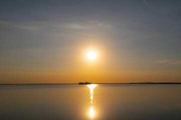 brilliant sun illuminates the sky above a tranquil lake