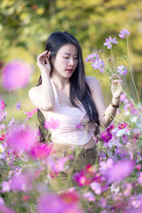 Wall Mural - Beautiful woman happy traveler walking in the flowers garden. Young woman smile and relaxing with happy  around outdoor garden. Woman's hand touching and enjoying beauty cosmos flowers.Travel concept.