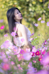 Wall Mural - Beautiful woman happy traveler walking in the flowers garden. Young woman smile and relaxing with happy  around outdoor garden. Woman's hand touching and enjoying beauty cosmos flowers.Travel concept.