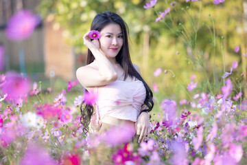Wall Mural - Beautiful woman happy traveler walking in the flowers garden. Young woman smile and relaxing with happy  around outdoor garden. Woman's hand touching and enjoying beauty cosmos flowers.Travel concept.