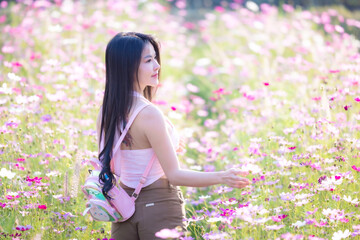 Wall Mural - Beautiful woman happy traveler walking in the flowers garden. Young woman smile and relaxing with happy  around outdoor garden. Woman's hand touching and enjoying beauty cosmos flowers.Travel concept.