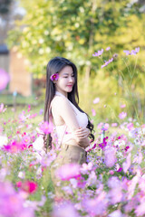 Wall Mural - Beautiful woman happy traveler walking in the flowers garden. Young woman smile and relaxing with happy  around outdoor garden. Woman's hand touching and enjoying beauty cosmos flowers.Travel concept.
