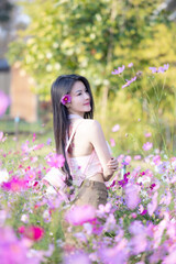 Wall Mural - Beautiful woman happy traveler walking in the flowers garden. Young woman smile and relaxing with happy  around outdoor garden. Woman's hand touching and enjoying beauty cosmos flowers.Travel concept.
