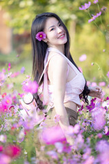 Wall Mural - Beautiful woman happy traveler walking in the flowers garden. Young woman smile and relaxing with happy  around outdoor garden. Woman's hand touching and enjoying beauty cosmos flowers.Travel concept.