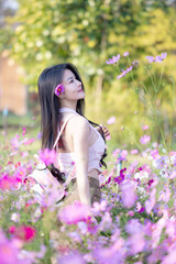 Wall Mural - Beautiful woman happy traveler walking in the flowers garden. Young woman smile and relaxing with happy  around outdoor garden. Woman's hand touching and enjoying beauty cosmos flowers.Travel concept.