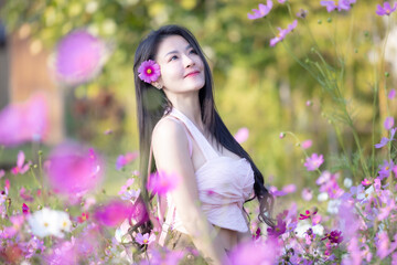 Wall Mural - Beautiful woman happy traveler walking in the flowers garden. Young woman smile and relaxing with happy  around outdoor garden. Woman's hand touching and enjoying beauty cosmos flowers.Travel concept.