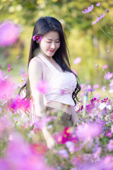 Wall Mural - Beautiful woman happy traveler walking in the flowers garden. Young woman smile and relaxing with happy  around outdoor garden. Woman's hand touching and enjoying beauty cosmos flowers.Travel concept.
