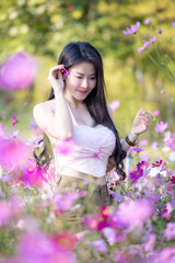 Wall Mural - Beautiful woman happy traveler walking in the flowers garden. Young woman smile and relaxing with happy  around outdoor garden. Woman's hand touching and enjoying beauty cosmos flowers.Travel concept.
