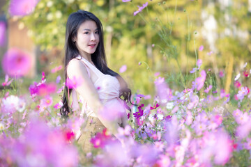 Wall Mural - Beautiful woman happy traveler walking in the flowers garden. Young woman smile and relaxing with happy  around outdoor garden. Woman's hand touching and enjoying beauty cosmos flowers.Travel concept.