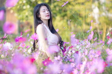 Wall Mural - Beautiful woman happy traveler walking in the flowers garden. Young woman smile and relaxing with happy  around outdoor garden. Woman's hand touching and enjoying beauty cosmos flowers.Travel concept.