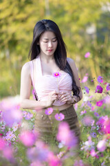 Wall Mural - Beautiful woman happy traveler walking in the flowers garden. Young woman smile and relaxing with happy  around outdoor garden. Woman's hand touching and enjoying beauty cosmos flowers.Travel concept.