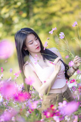 Wall Mural - Beautiful woman happy traveler walking in the flowers garden. Young woman smile and relaxing with happy  around outdoor garden. Woman's hand touching and enjoying beauty cosmos flowers.Travel concept.