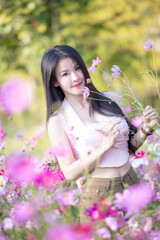 Wall Mural - Beautiful woman happy traveler walking in the flowers garden. Young woman smile and relaxing with happy  around outdoor garden. Woman's hand touching and enjoying beauty cosmos flowers.Travel concept.