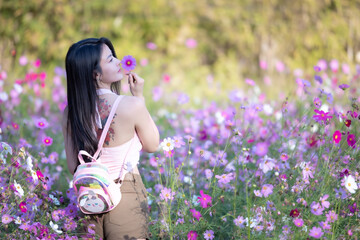 Wall Mural - Beautiful woman happy traveler walking in the flowers garden. Young woman smile and relaxing with happy  around outdoor garden. Woman's hand touching and enjoying beauty cosmos flowers.Travel concept.