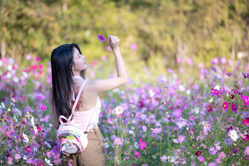 Wall Mural - Beautiful woman happy traveler walking in the flowers garden. Young woman smile and relaxing with happy  around outdoor garden. Woman's hand touching and enjoying beauty cosmos flowers.Travel concept.