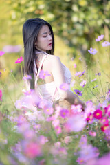 Wall Mural - Beautiful woman happy traveler walking in the flowers garden. Young woman smile and relaxing with happy  around outdoor garden. Woman's hand touching and enjoying beauty cosmos flowers.Travel concept.