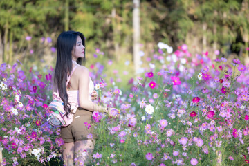 Wall Mural - Beautiful woman happy traveler walking in the flowers garden. Young woman smile and relaxing with happy  around outdoor garden. Woman's hand touching and enjoying beauty cosmos flowers.Travel concept.