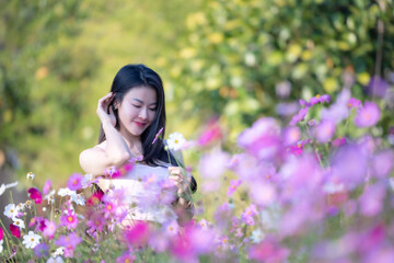 Wall Mural - Beautiful woman happy traveler walking in the flowers garden. Young woman smile and relaxing with happy  around outdoor garden. Woman's hand touching and enjoying beauty cosmos flowers.Travel concept.