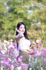 Wall Mural - Beautiful woman happy traveler walking in the flowers garden. Young woman smile and relaxing with happy  around outdoor garden. Woman's hand touching and enjoying beauty cosmos flowers.Travel concept.