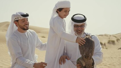 Wall Mural - Three generation family spending time in the desert with the falcon bird making a safari in Dubai. Concept about middle eastern cultures and lifestyle in the emirates