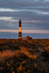 Sticker - Scenic view of a lighthouse in the distance, set against a backdrop of dark clouds